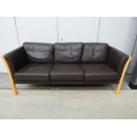 A Danish beech framed three-seater sofa with brown leather upholstery *Sold subject to our Soft