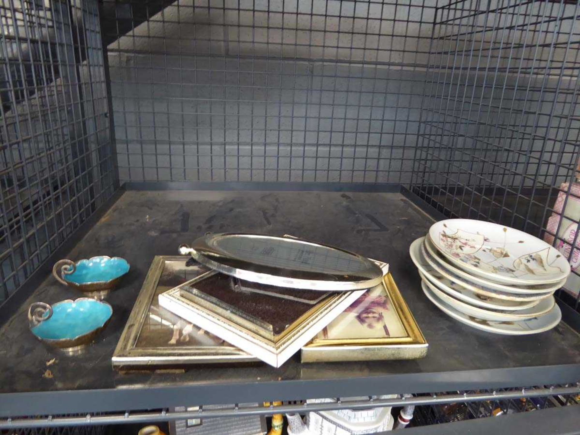Cage containing photo frames and oriental dishes