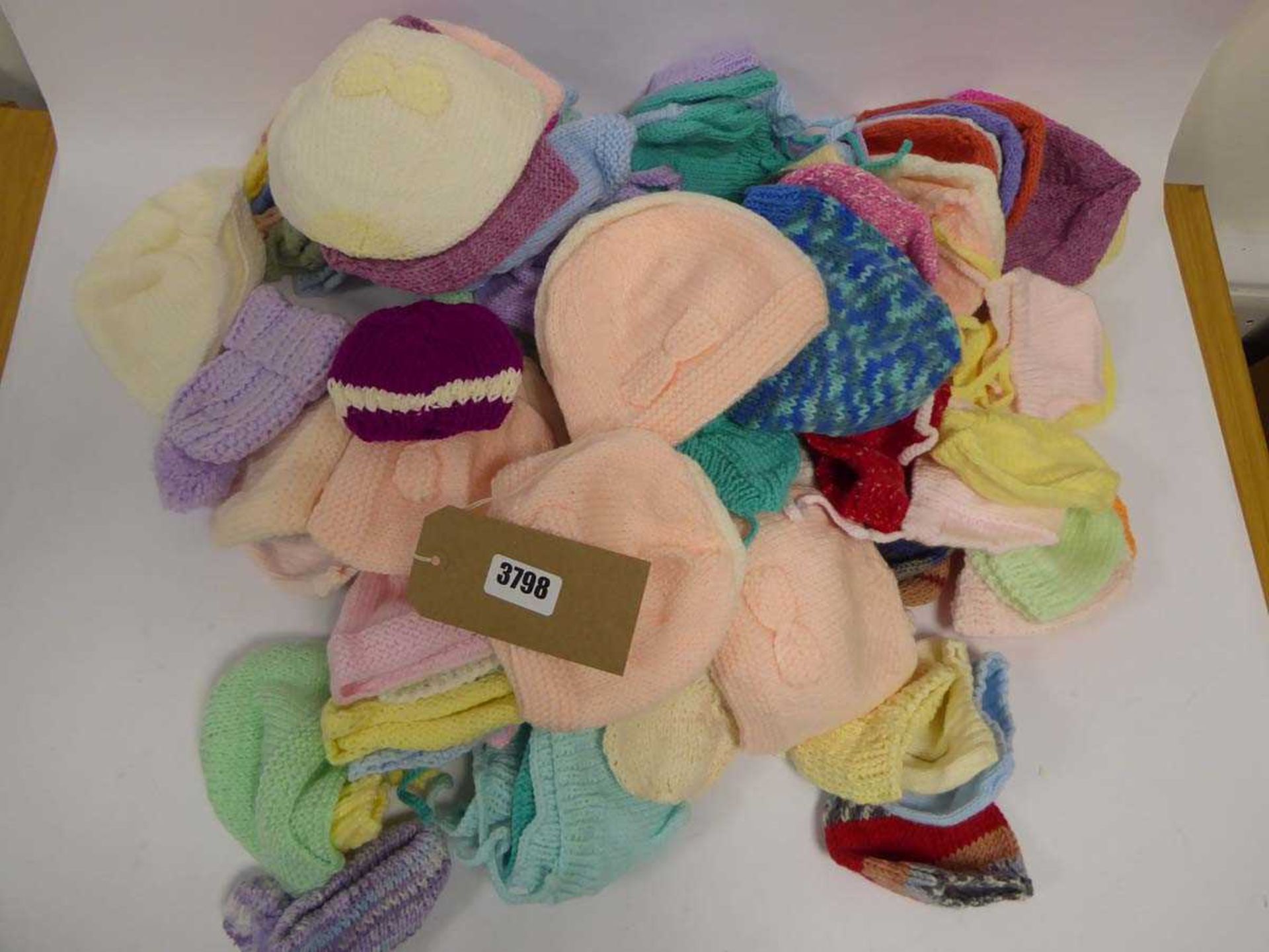 Bag containing selection of hand knitted baby bonnets