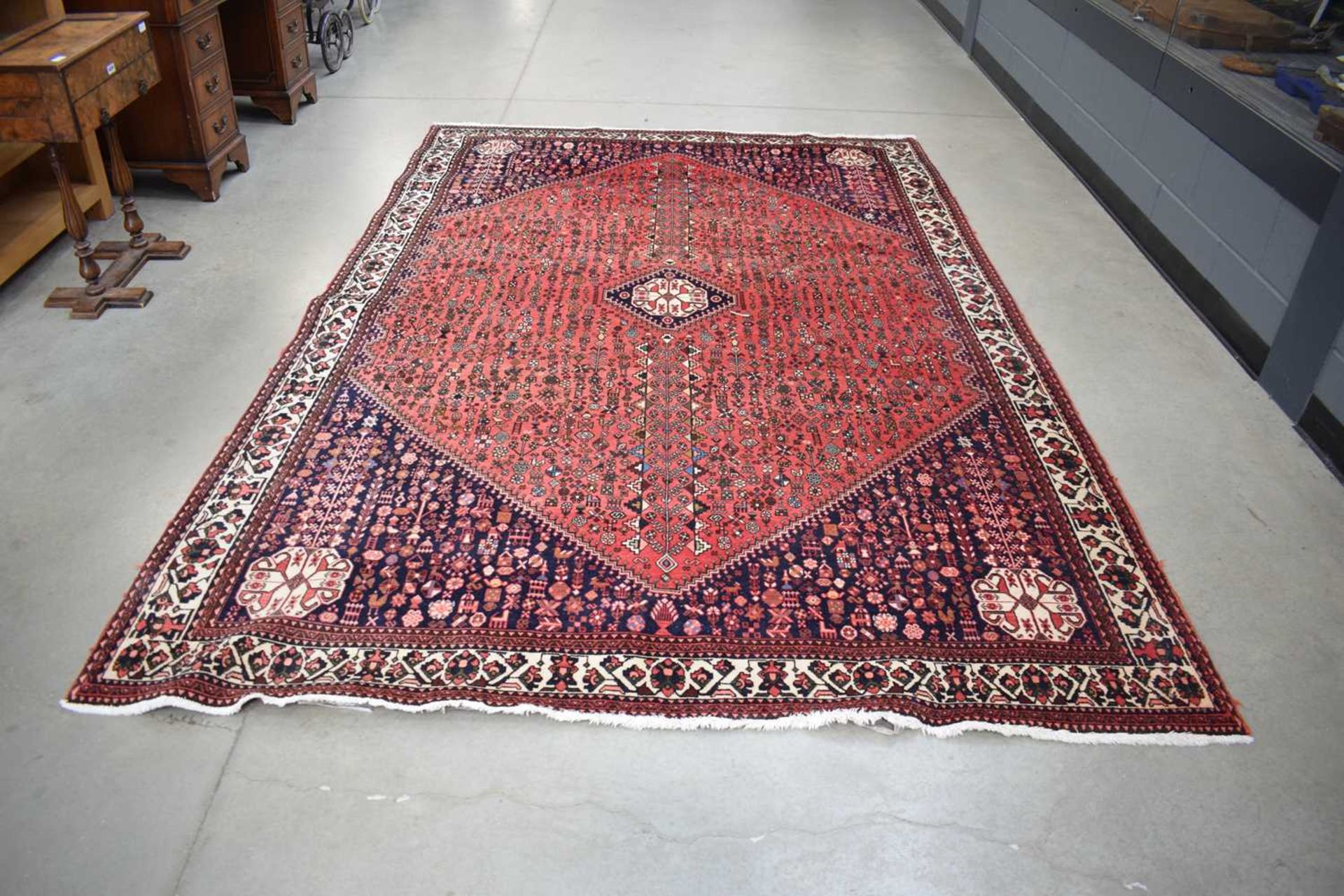 A Persian 'Abadeh' carpet, hand-woven in Iran, with a red ground and stylied motifs, 307 x 204 cm