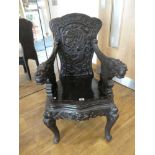 Heavily carved dark stained wooden armchair of Asian design