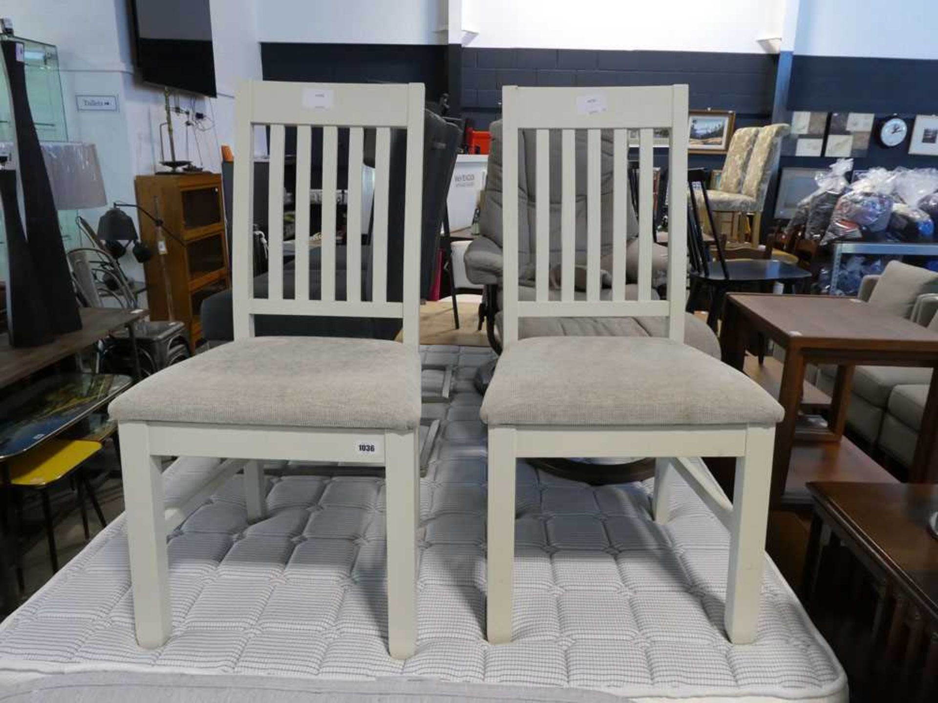 Modern pair of white slat back dining chairs with beige upholstered seats