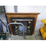 Cast iron decorative fire place flanked by floral themed tiles with wooden mantle piece