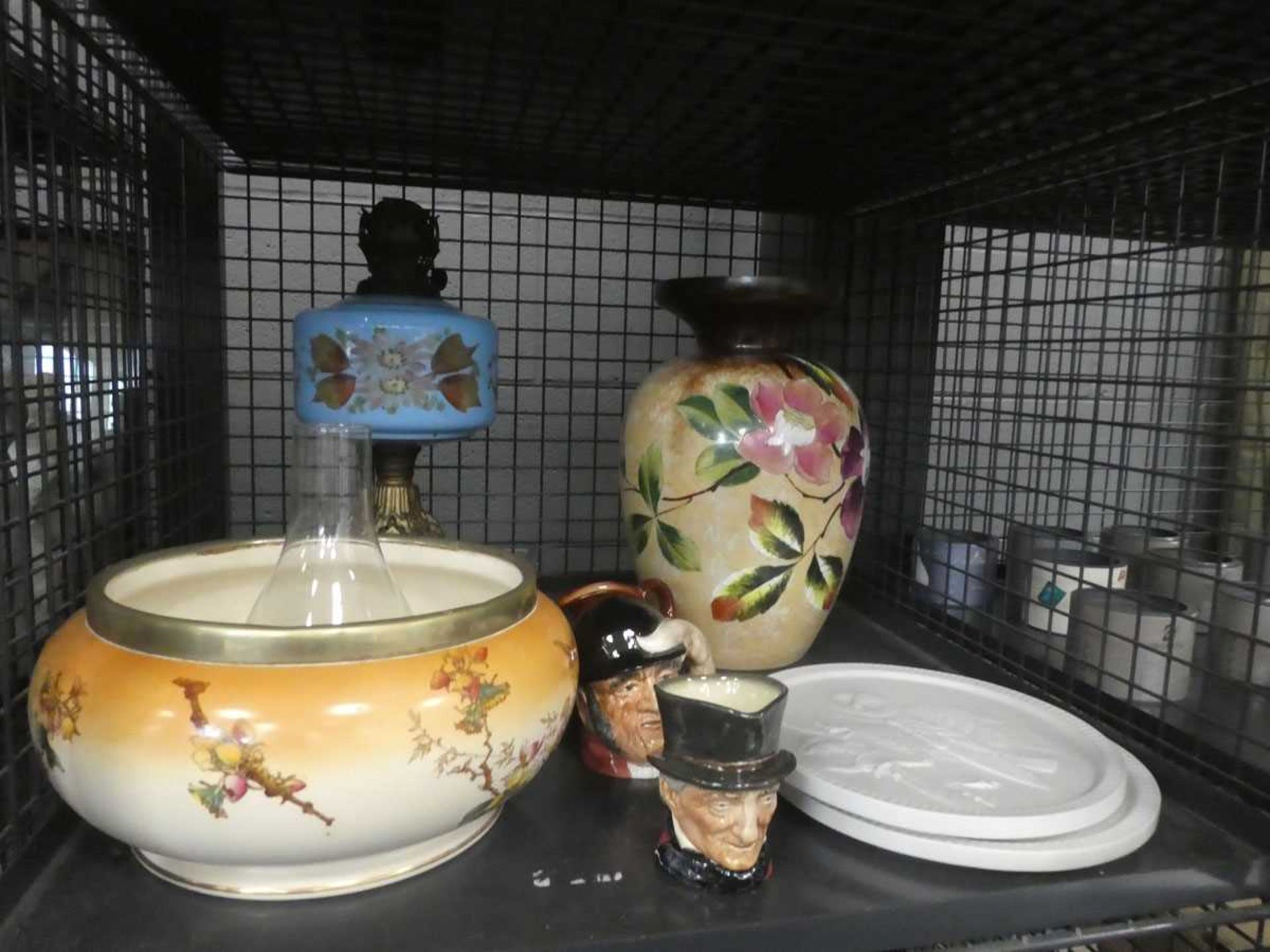 Cage containing fruit bowl, bird patterned plaques, miniature Toby jugs, brass oil lamps, and floral