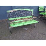 Slatted wood garden bench in green with cast metal ends and floral back panel