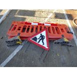 Three plastic road barriers and work sign