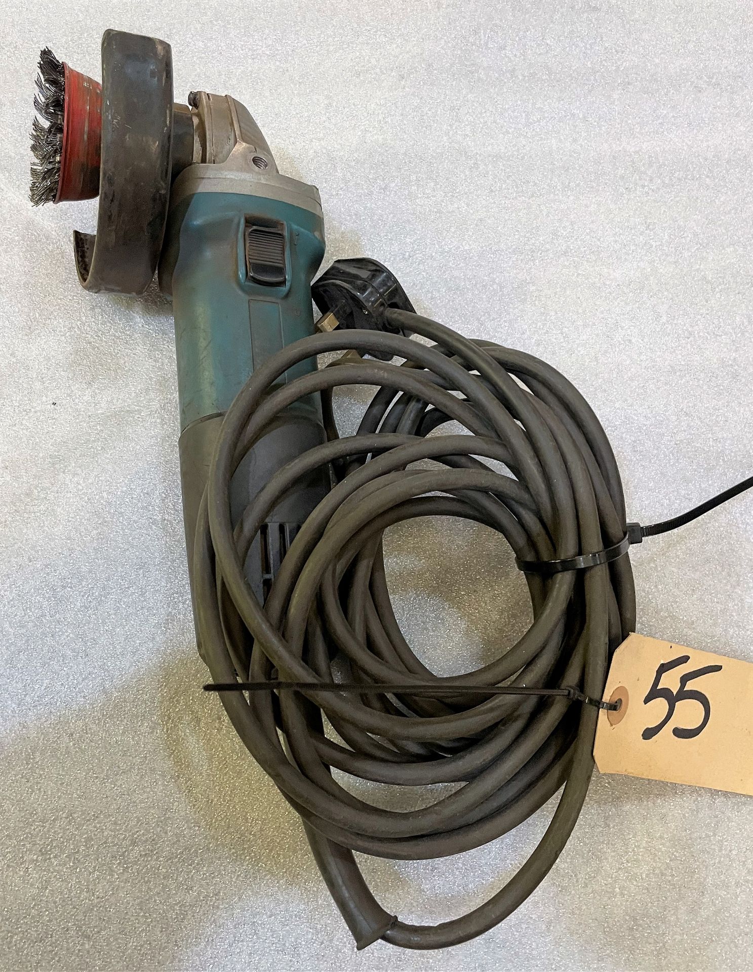 A Makita 9557NB 115mm Angle Grinder, 240v with wire wheel.