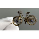 A BICYCLE PIN BROOCH, yellow metal encrusted with two small sapphires and a diamond headlight.