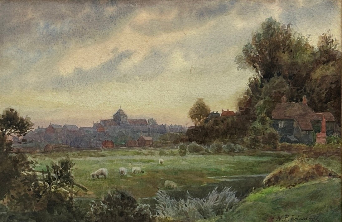 A WATERCOLOUR SCENE OF FIELDS LOOKING TOWARDS A VILLAGE, signed N.P Edwards, mounted in a frame