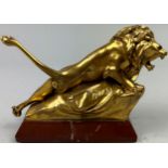 A SCULPTURAL GILT BRONZE OF A LION, mounted on a red marble base and signed indistinctly.