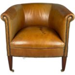 A BROWN LEATHER TUB CHAIR, raised on legs terminating in brass castors
