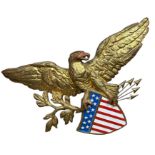 A GILT PAINTED AMERICAN EAGLE WALL HANGING, above a United States Stars and Stripes with five