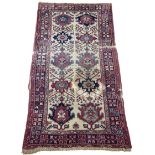 AN ANTIQUE PERSIAN RUG, With signs of wear and marks throughout. 225cm x 125cm