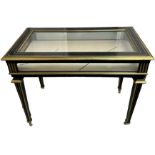 AN EBONISED AND BRASS VITRINE TABLE, late 19th Century. With hinged top, silk lining, raised on