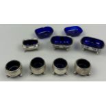 A COLLECTION OF SILVER SALT CELLARS AND MUSTARD POTS, each with blue glass inserts (7) The salt