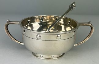 AN UNUSUAL ARTS AND CRAFTS SILVER TWO HANDLE BOWL AND SPOON WITH EMBOSSED ROUNDELS DATED 1927, By