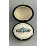 A PLATINUM RING INSET WITH A BLUE GEMSTONE most likely aquamarine, within a small black case.