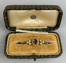 A GOLD BROOCH, Inset with amethyst surrounded by a rope twist border and flanked by two clusters