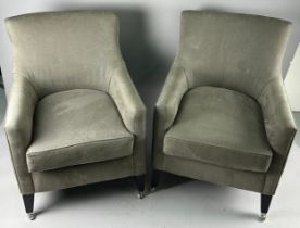 A PAIR OF GREY UPHOLSTERED ARMCHAIRS raised on ebonised legs with castors.