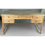 A LIMED WOOD AND CANE DRESSING TABLE WITH GLASS TOP, Five drawers raised upon four carved acanthus