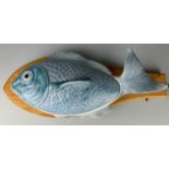 A LARGE CERAMIC FISH ON A SHAPED HANDMADE WOODEN PLATTER