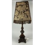AN 18TH CENTURY TURNED OAK CANDLESTICK ADAPTED INTO A LAMP WITH EARLIER TAPESTRY SHADE 65cm H
