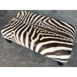 A LARGE ZEBRA SKIN CENTRE STOOL WITH STUDDED DETAILING, raised on four legs