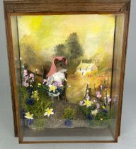 A TAXIDERMY CASED DIORAMA BY TONY ARMISTEAD OF A MOUSE CARRYING A BASKET OF FLOWERS AND WALKING ON A