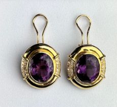 A PAIR OF OVAL SHAPED AMETHYST EARRINGS IN 18CT GOLD, each flanked by clusters of small diamonds.