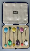 A SET OF SIX SILVER AND COLOURED GUILLOCHE ENAMEL SPOONS, In an antique harrods case. 45gms