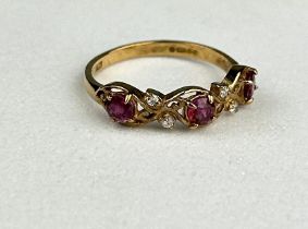 A 9CT GOLD RING INSET WITH THREE SMALL RUBIES AND FOUR SMALL DIAMONDS