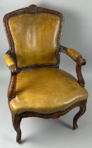 A 19TH CENTURY FRENCH WALNUT FAUTEUIL, The shaped back tan leather upholstered with carved flower