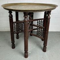 A 19TH CENTURY MOROCCAN FOLDING TABLE, with a brass tray top, 64cm diameter x 57.5cm h Used