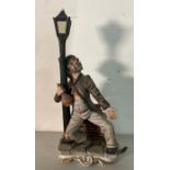 A china hand painted figure of an over refreshed reveler gripping a lamp post, signed