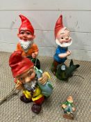 Three garden gnomes, two with fish and one on a swing