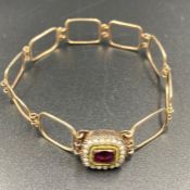 A gold bracelet with garnet and seed pearl decoration