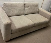 A beige two seater sofa (H100cm W185cm D100cm)