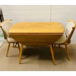 A blonde ercol table and two chairs