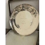 A white metal serving plate or charger with fruit decoration to rim