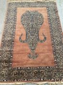 A brown ground wool rug with central medallion and geometric border red and blues (130cm x 210cm)