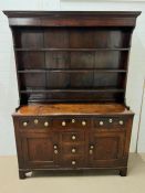 A George III stained dresser, the shelved rack above three drawers and two panelled cupboard doors