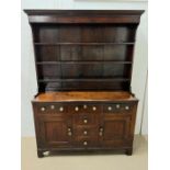 A George III stained dresser, the shelved rack above three drawers and two panelled cupboard doors