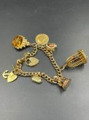 A 9ct gold charm bracelet with a selection of charms including a 1914 half sovereign (Approximate
