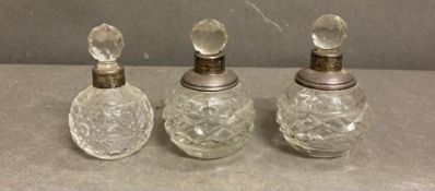 Three glass scent bottles with silver hallmarked collars