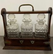 An oak tantalus with three cut glass decanters