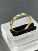 An emerald and diamond ring with four sapphire and three diamonds on an untested gold band. Size X