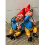 Two garden gnomes climbing up ropes