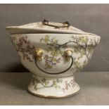 A china warmer, decorated with cherry blossom. and loop handles to lid and base.