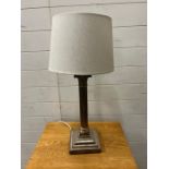 A white metal Corinthian column table lamp with swags and ram head corners to base