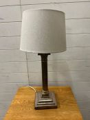 A white metal Corinthian column table lamp with swags and ram head corners to base
